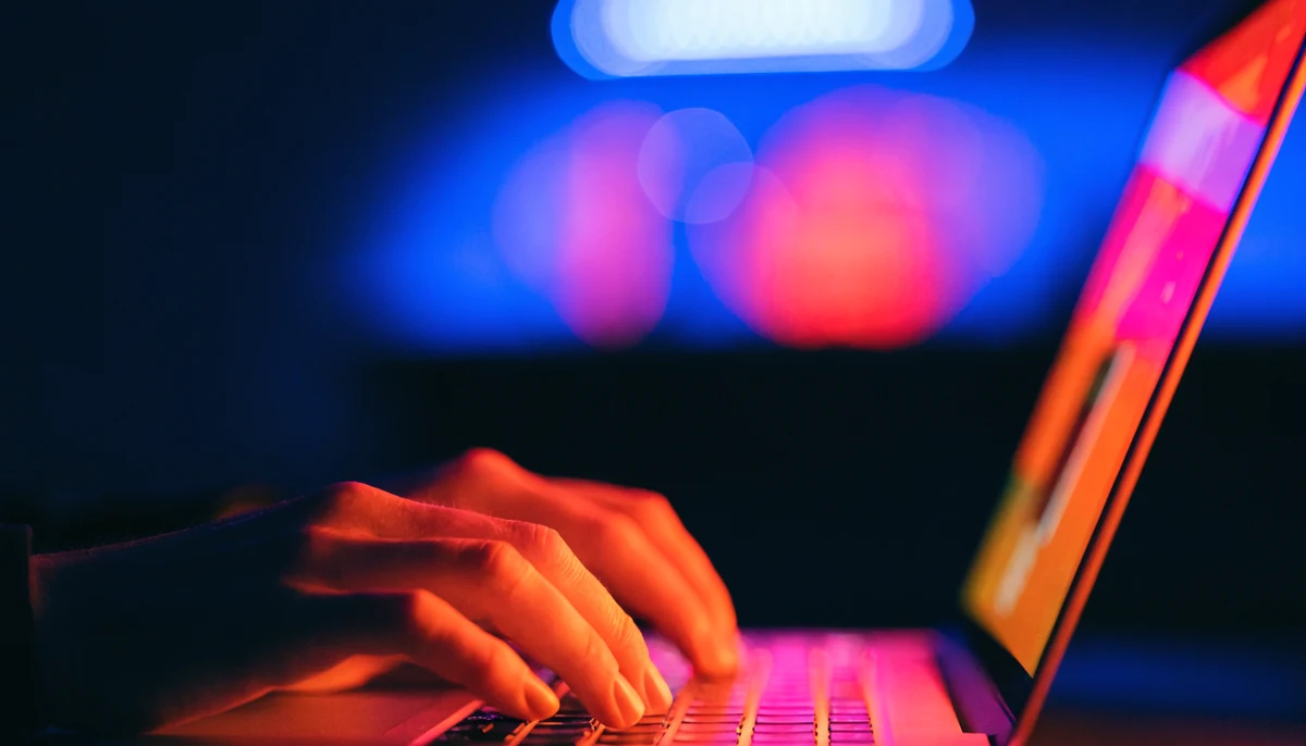 Mains sur un clavier d’ordinateur portable dans la lumière d’un écran